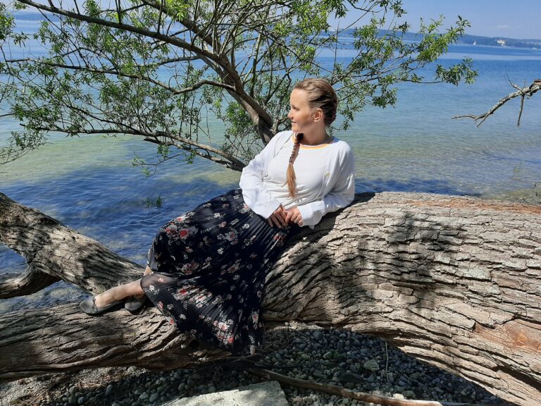Bettina Kunze liegt auf einem Baumstamm direkt an einem See